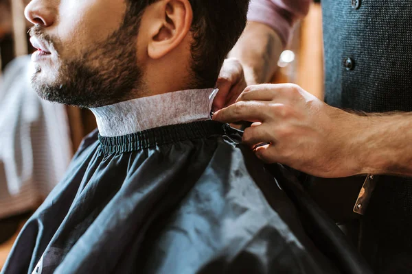 Cropped view of barber fixing collar around neck of man — Stock Photo