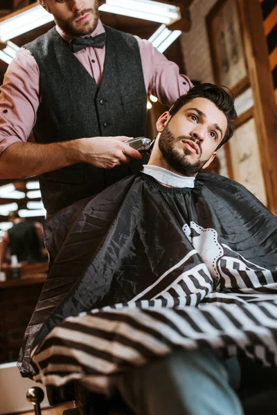 Selektiver Fokus der stilvollen Friseur Halter Trimmer beim Styling Haare des Mannes — Stockfoto