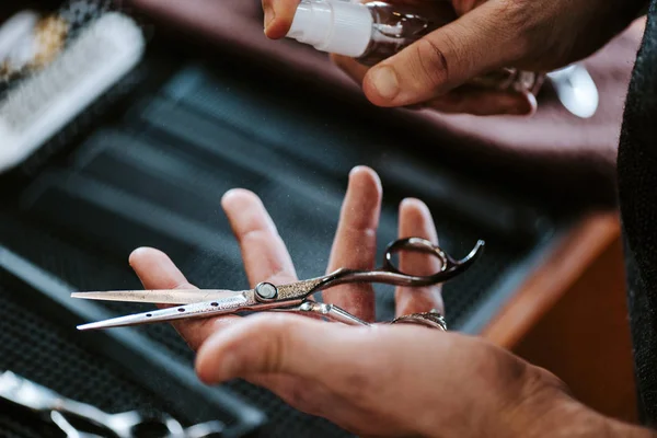 Abgeschnittene Ansicht eines Friseurs, der antibakterielles Spray in der Nähe der Schere hält — Stockfoto