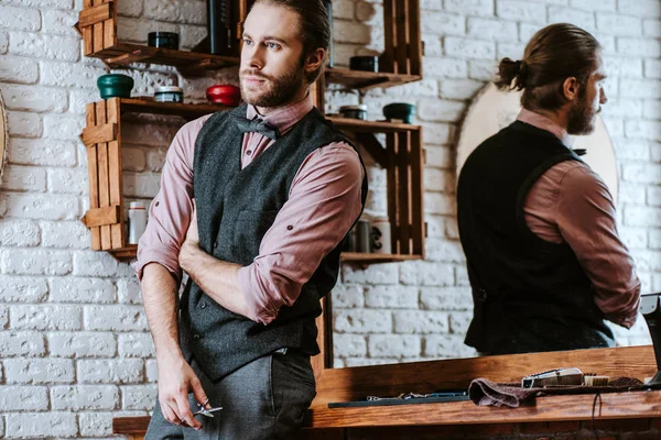 Barbudo y guapo peluquero celebración de tijeras en la barbería - foto de stock