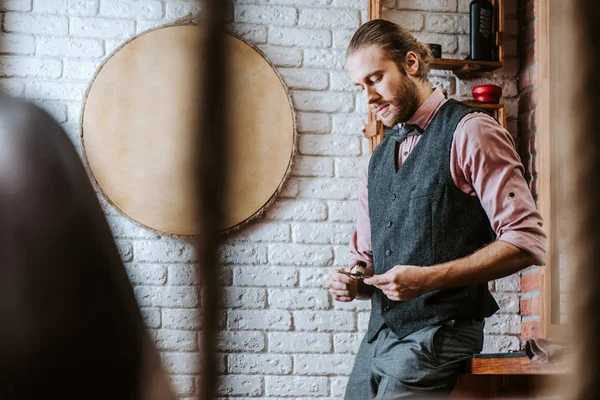 Selektiver Fokus eines gutaussehenden Friseurs, der im Friseurladen eine Schere in der Hand hält — Stockfoto
