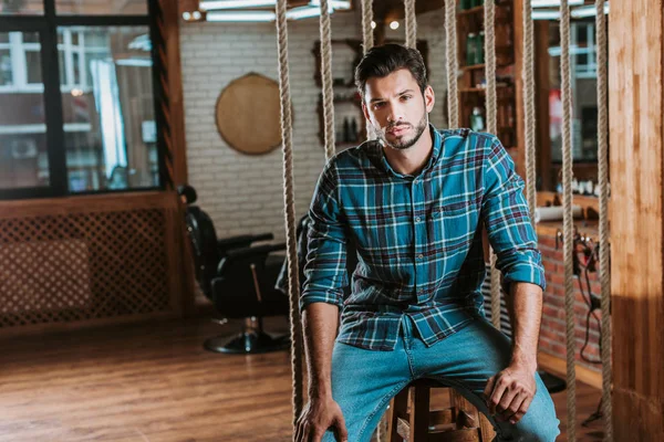 Ernsthafter Friseur sitzt und schaut in die Kamera — Stockfoto