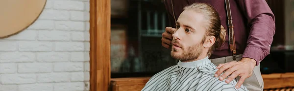 Plano panorámico de peluquero tocando el pelo de hombre guapo en la barbería - foto de stock