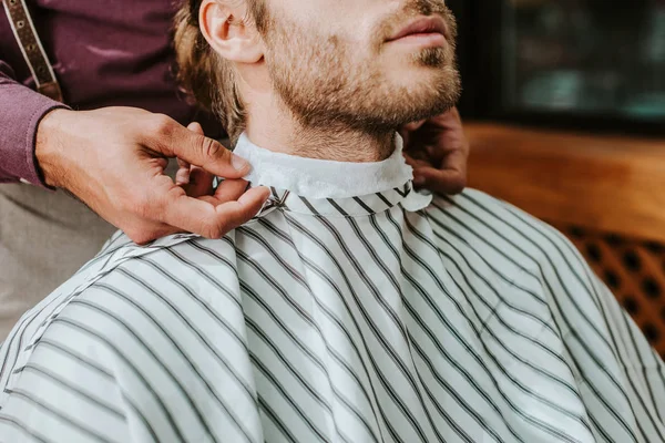 Cropped view of barber fixing collar around neck of man — Stock Photo