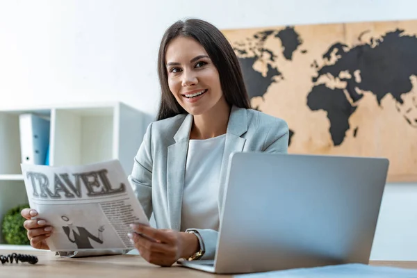 Attraktives Reisebüro mit Reisezeitung und Blick in die Kamera — Stockfoto