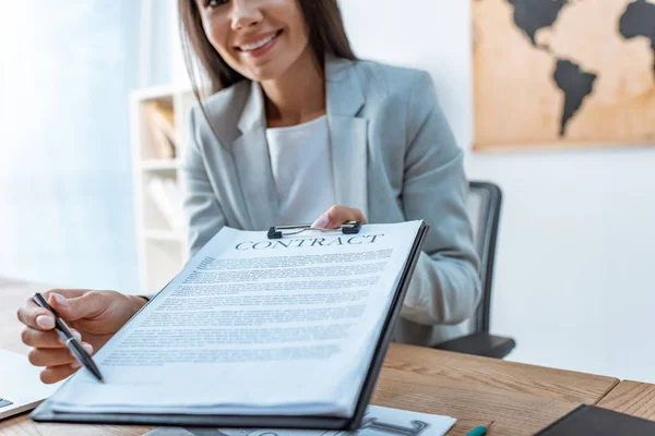 Vue recadrée de l'agent de voyage souriant pointant avec stylo au lieu de signature dans le contrat — Photo de stock