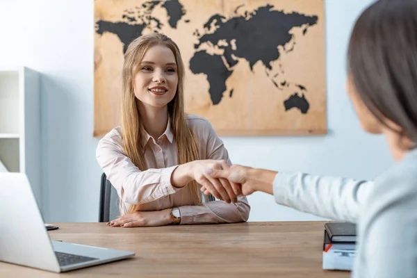 Attraente, sorridente agente di viaggio stringendo la mano con il cliente — Foto stock