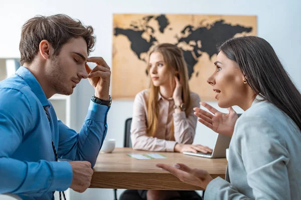 Selective focus of quarreling couple of tourists near bored travel agent — Stock Photo