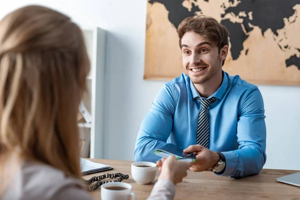 Selective focus of smiling travel agent giving passports and air tickets to client — Stock Photo