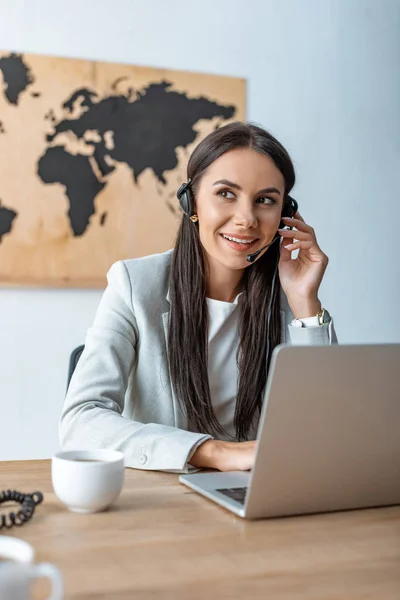 Smiling travel agent working near laptop — Stock Photo