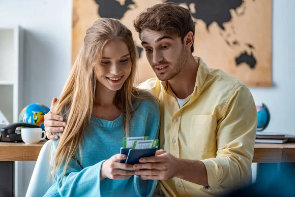 Happy couple of tourists looking at passports and air tickets in travel agency — Stock Photo