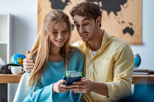 Feliz pareja de turistas mirando pasaportes y billetes de avión en la agencia de viajes - foto de stock