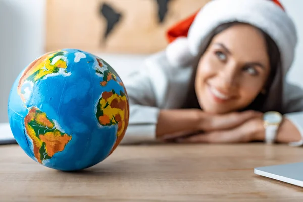 Smiling, dreamy travel agent looking away near globe at workplace — Stock Photo