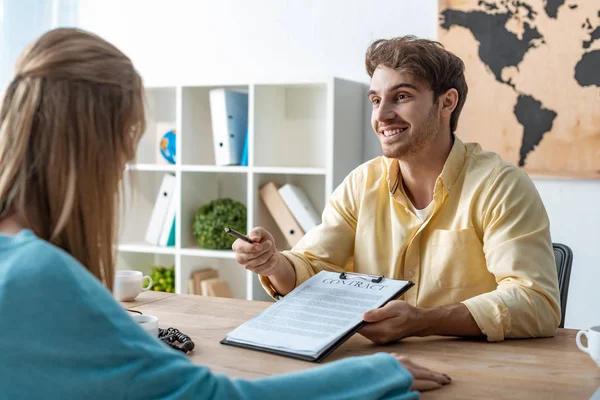 Smiling travel agent giving contract and pen to client — Stock Photo