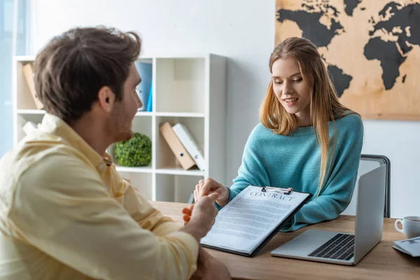 Attractive, smiling travel agent showing contract to client — Stock Photo