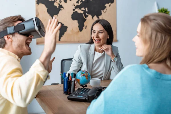 Excited young man using vr headset near girlfriend and travel agent — Stock Photo