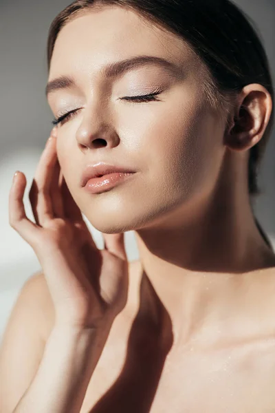 Attractive naked young woman with closed eyes on grey — Stock Photo