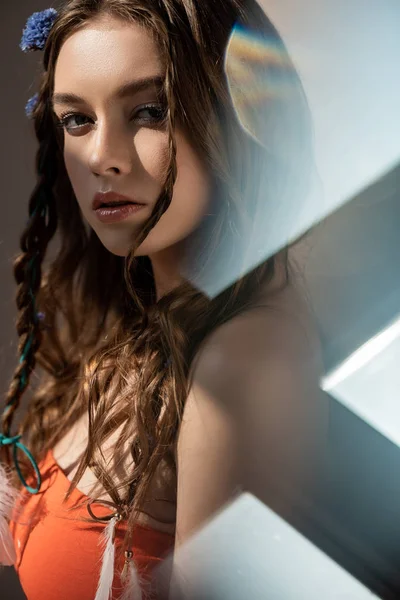 Bela menina étnica com tranças no penteado posando em cinza com flares de lente — Fotografia de Stock