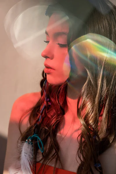 Zartes Boho-Mädchen mit Zöpfen in Frisur posiert im Rotlicht mit Linsenraketen — Stockfoto