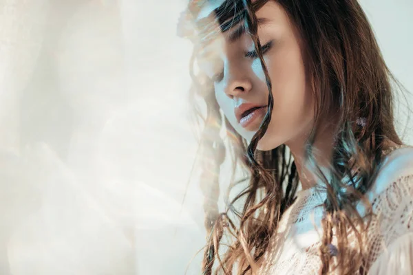 Tierna joven con trenzas en peinado posando en vestido boho blanco sobre gris con destellos de lente - foto de stock