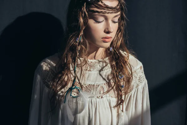 Junge zarte Frau mit Zöpfen und geschlossenen Augen in weißem Boho-Kleid auf grau — Stockfoto