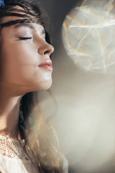 Menina boho atraente com tranças no penteado posando com olhos fechados em cinza com flares de lente — Fotografia de Stock