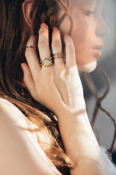 Бохо дівчина з косами в зачісці і кільцями на руці позує на сірому з спалахами лінз — стокове фото