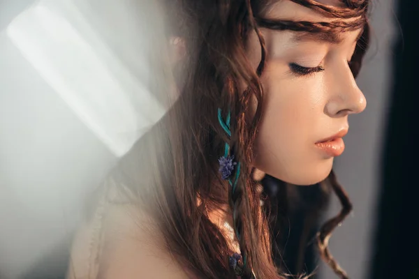 Tierna chica boho con trenzas en peinado posando sobre gris con bengalas de lente - foto de stock