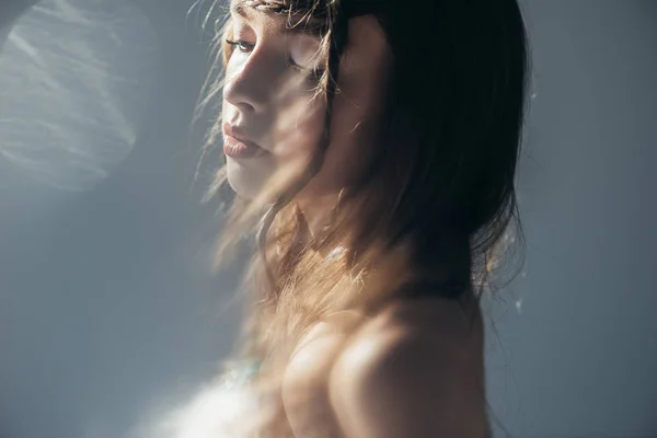 Tierna chica boho con trenzas en peinado posando sobre gris con bengalas de lente - foto de stock