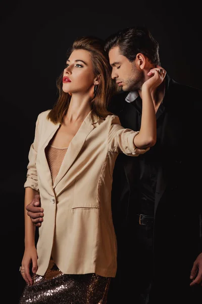 Schöner Mann im Anzug umarmt attraktive Frau isoliert auf schwarz — Stockfoto