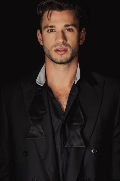 Handsome man in suit looking at camera isolated on black — Stock Photo