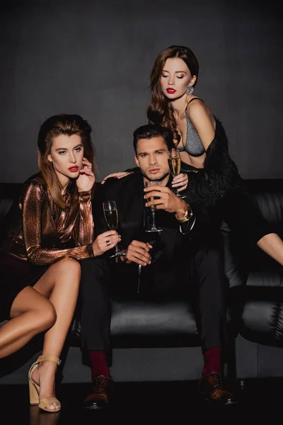 Attractive women and handsome man holding champagne glasses isolated on black — Stock Photo