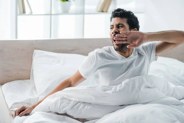 Красивый двурасовый мужчина зевает и просыпается утром — стоковое фото