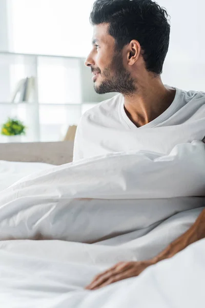 Hombre bi-racial guapo y sonriente mirando hacia otro lado en la mañana - foto de stock