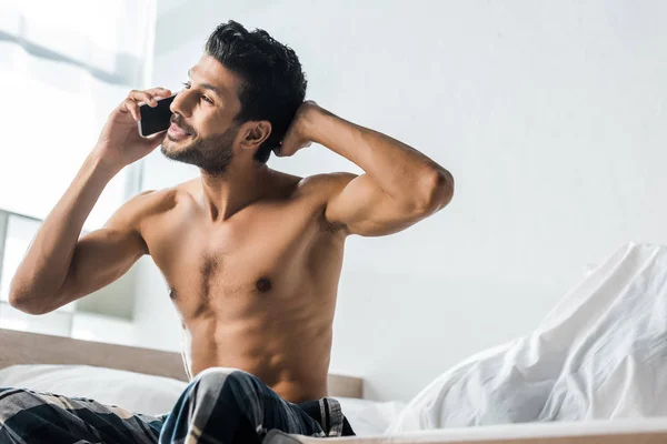 Красивый и улыбающийся двурасовый мужчина разговаривает по утрам на смартфоне — стоковое фото