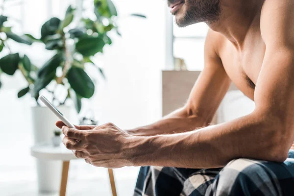 Cropped view of smiling bi-racial man using smartphone in morning — Stock Photo