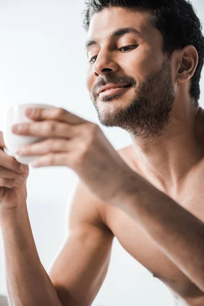 Messa a fuoco selettiva di bello e sorridente uomo bi-razziale in possesso di una tazza di caffè al mattino — Foto stock