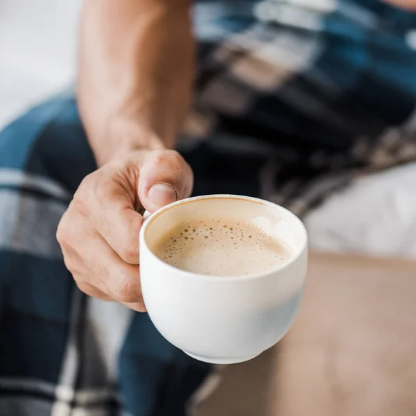 Vista cortada de homem bi-racial segurando xícara de café de manhã — Fotografia de Stock