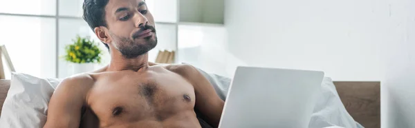 Panoramic shot of handsome and sexy bi-racial man using laptop in morning — Stock Photo