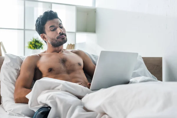 Guapo y sexy bi-racial hombre usando el ordenador portátil en la mañana - foto de stock