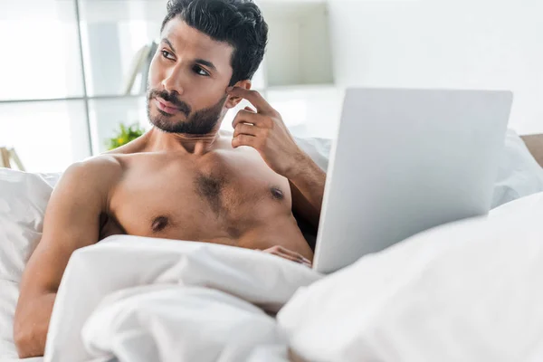Homme bi-racial beau et coûteux avec ordinateur portable regardant loin le matin — Photo de stock