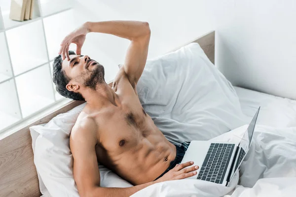 Высокий угол обзора красивого и задумчивого двурасового мужчины с ноутбуком утром — стоковое фото