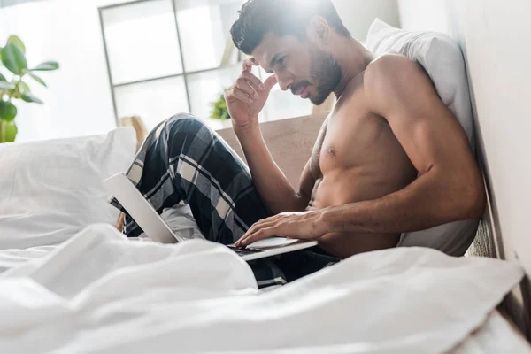 Вид збоку красивий і стомлений бі-расовий чоловік використовує ноутбук вранці — стокове фото