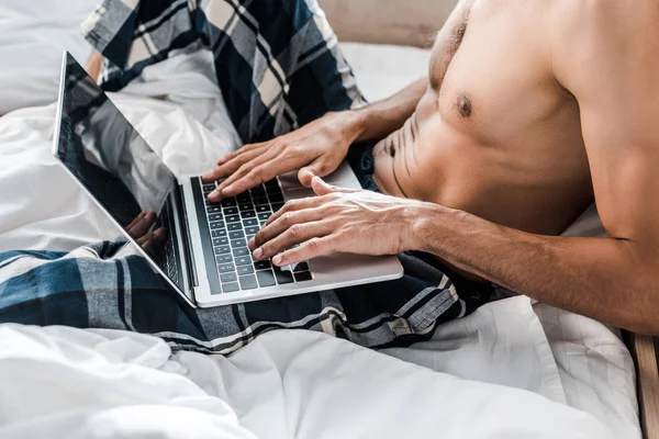 Cropped view of sexy bi-racial man using laptop in morning — Stock Photo