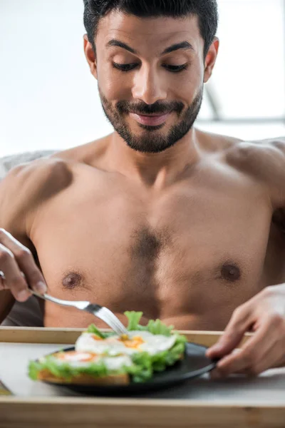 Hombre bi-racial guapo y sonriente desayunando por la mañana - foto de stock