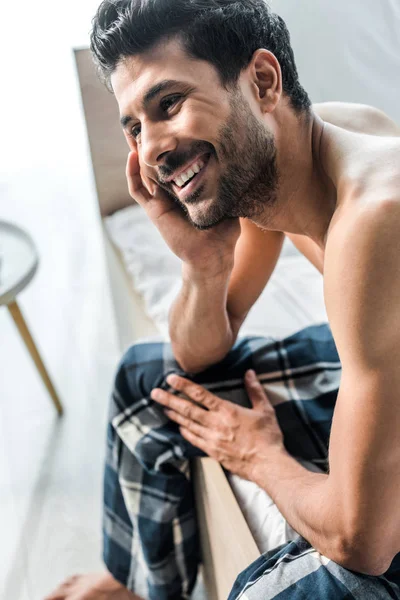 Handsome and smiling bi-racial man sitting on bed in morning — Stock Photo