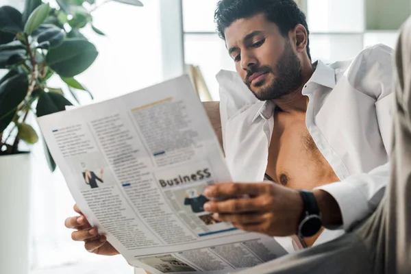 Enfoque selectivo de guapo bi-racial hombre leyendo periódico en la mañana - foto de stock