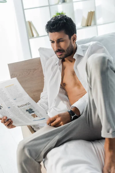 Bel homme bi-racial lisant le journal sur le lit le matin — Photo de stock