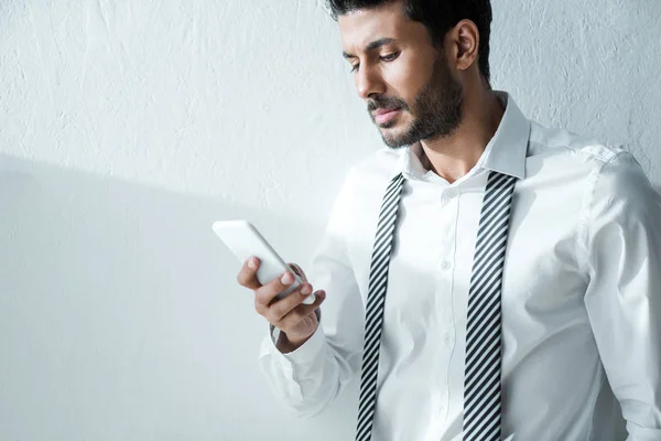 Guapo bi-racial hombre de negocios utilizando el teléfono inteligente en la mañana en casa - foto de stock