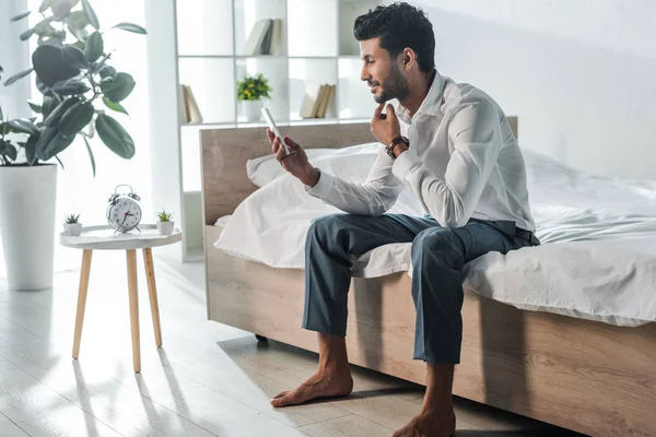 Handsome and smiling bi-racial businessman using smartphone in morning at home — Stock Photo